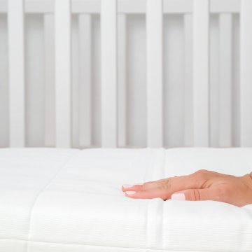 Hand on baby crib mattress
